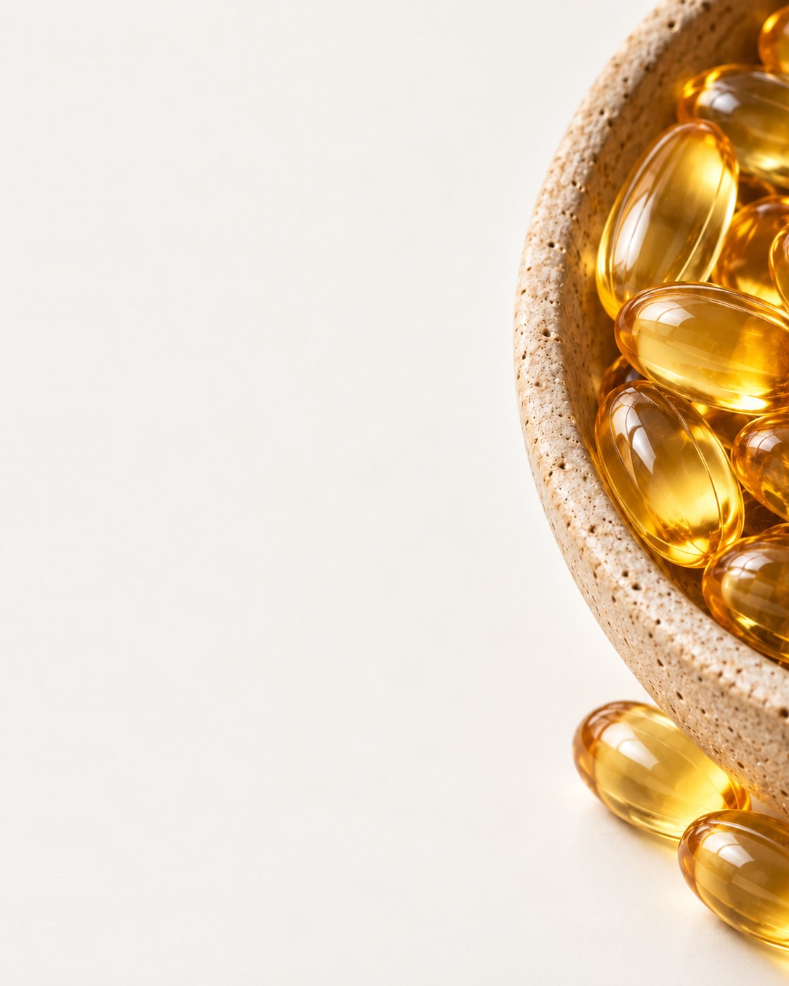 Close-up of golden fish-oil capsules in a stoneware dish for the Healthy department